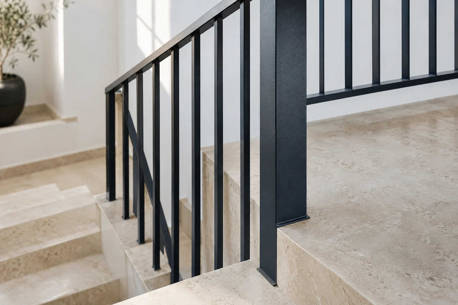 Encuentro de una barandilla metálica oscura con el rellano de una escalera interior.
