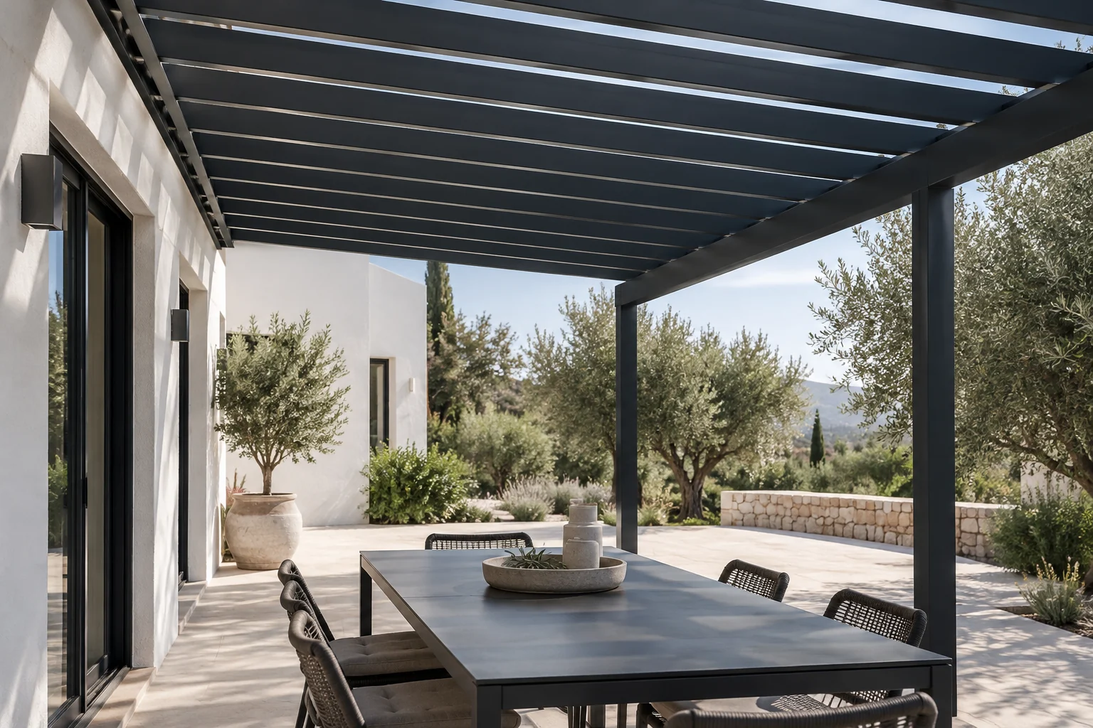 Vista bajo una pérgola antracita con vigas paralelas y una mesa de exterior.